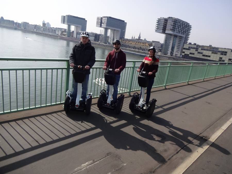 Drei Segway Fahrer in Köln auf einer Brücke vor den Kranhäusern