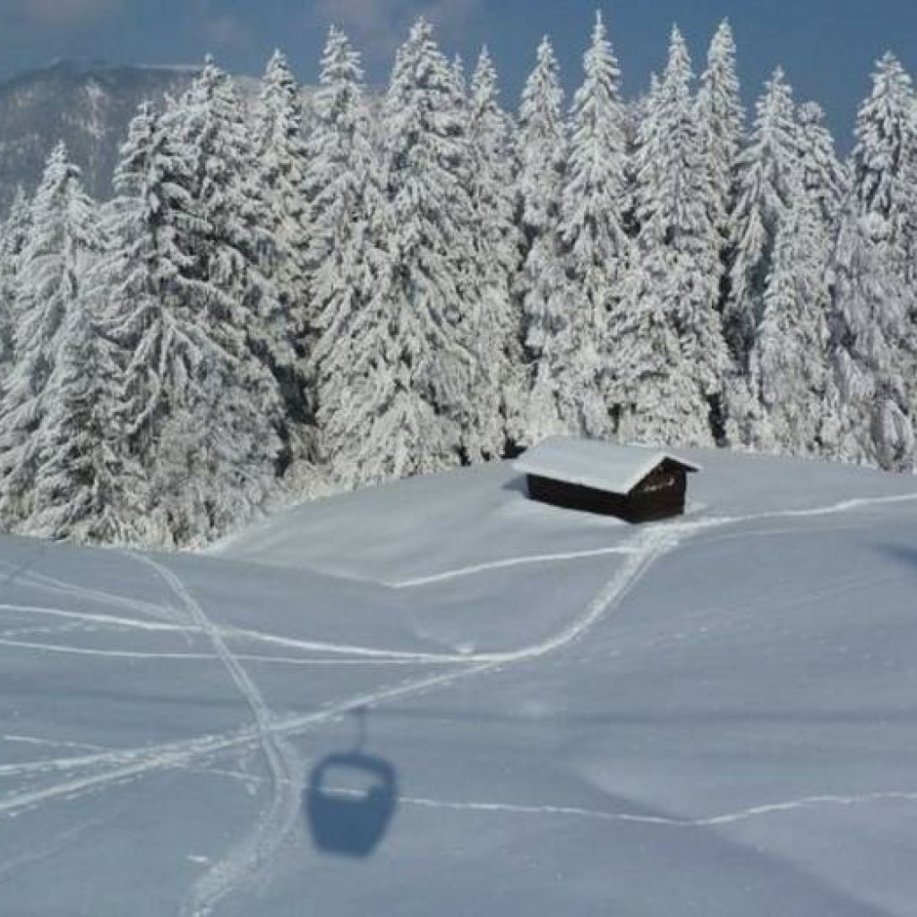 Schatten einer Gondel über Tal im Schnee