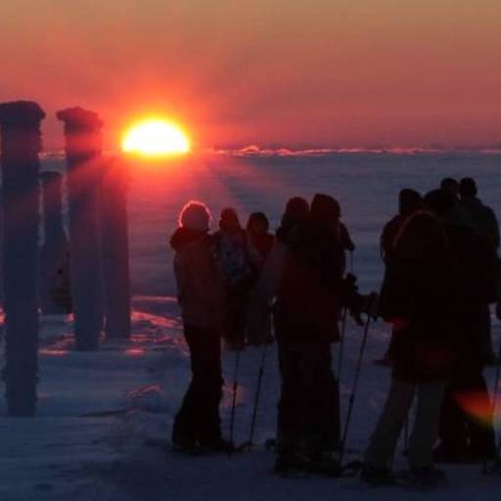 Gruppe von Schneeschuhwanderern beim Sonnenaufgang
